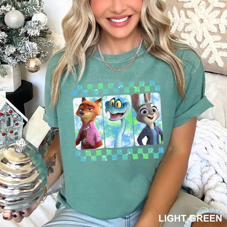 May include: Light green t-shirt featuring three cartoon characters in rectangular frames with a checkered border. The characters are a fox, a snake, and a rabbit. The text "LIGHT GREEN" is at the bottom.