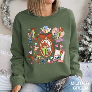 Puede incluir: Sudadera verde militar con personajes de dibujos animados de Zootopia. El dise&ntilde;o incluye a Nick Wilde y Judy Hopps, con el texto "Best Friends Forever" y "Bestie". La sudadera tiene cuello redondo y mangas largas.
