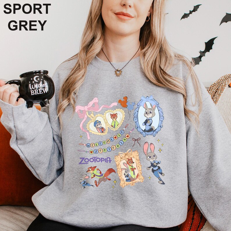 May include: Sport grey sweatshirt featuring Zootopia characters and the word "Zootopia". The design includes framed images of Judy Hopps and Nick Wilde, along with other characters and the phrase "Welcome to Zootopia".