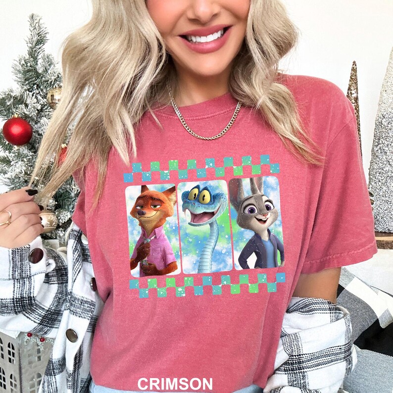 May include: Crimson-colored t-shirt featuring a graphic of three animated characters: a fox, a snake, and a rabbit. The graphic is framed with a green and blue checkered pattern. The word "CRIMSON" is printed at the bottom of the shirt.
