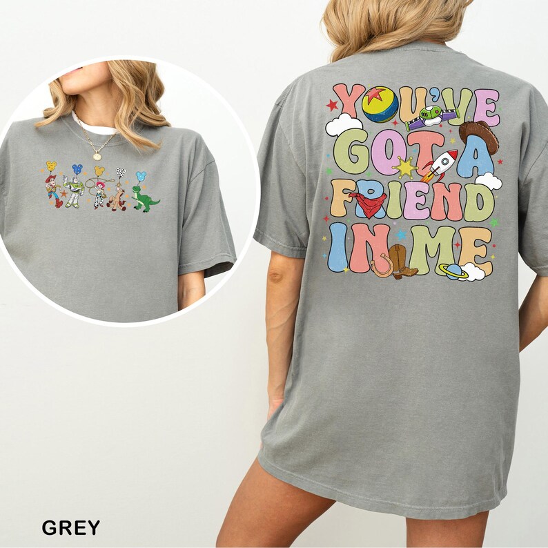 May include: Grey t-shirt featuring cartoon characters on the front and the phrase "You've Got A Friend In Me" on the back. The shirt has a loose fit.
