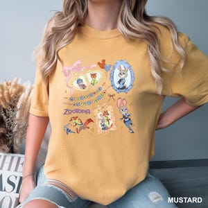 May include: Mustard-colored t-shirt featuring cartoon characters from the movie Zootopia. The shirt has a graphic design with framed images of the characters, the word "Zootopia", and the phrase "Welcome to Zootopia".