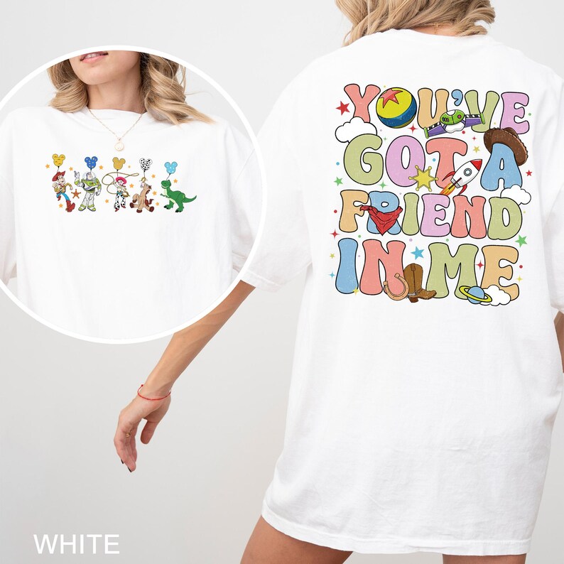 May include: White t-shirt with a colourful Toy Story design, including characters and the text "You've Got A Friend In Me." The graphic features a cowboy hat, rocket, and other playful elements. The shirt has a relaxed fit.