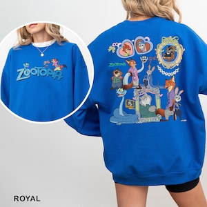 K&ouml;nnte beinhalten: K&ouml;nigsblaues Sweatshirt mit dem Wort "Zootopia" in T&uuml;rkis auf der Vorderseite. Auf der R&uuml;ckseite befindet sich eine farbenfrohe Grafik von Zootopia-Charakteren. Ein bequemes, l&auml;ssiges Sweatshirt.