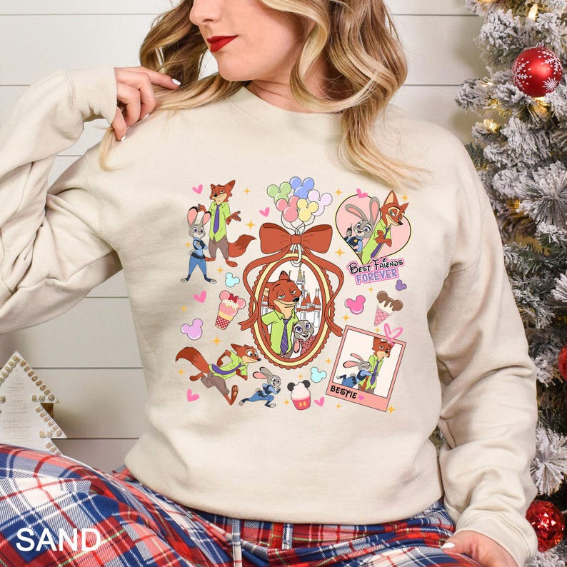Puede incluir: Sudadera de color arena con personajes de dibujos animados y el texto "Best Friends Forever" y "Bestie". El dise&ntilde;o incluye un zorro y un conejo, globos, helados y corazones. La sudadera tiene mangas largas.