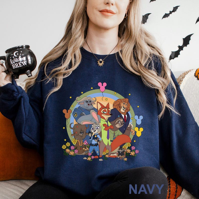 May include: Navy blue sweatshirt featuring a colorful cartoon graphic of animal characters. The design includes a rainbow, flowers, and Mickey Mouse-shaped balloons. The word "NAVY" is printed at the bottom.