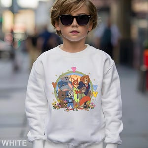 May include: White sweatshirt featuring a colorful graphic of animated animal characters. The design includes a rainbow, flowers, and Mickey Mouse-shaped balloons. The word "WHITE" is printed at the bottom left corner of the sweatshirt.