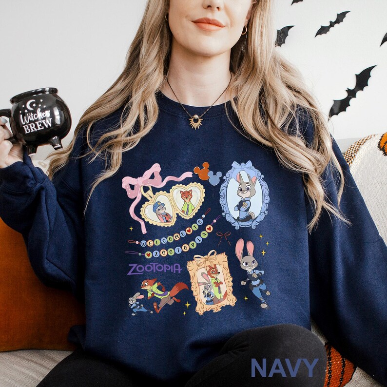 May include: Navy blue sweatshirt featuring colorful cartoon images of characters from the movie Zootopia. The design includes framed portraits, a pink bow, and the word "Zootopia". The word "NAVY" is printed at the bottom.