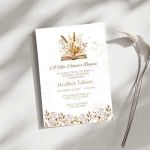 Op de afbeelding: Een witte uitnodigingskaart met gouden tekst en een aquarel-illustratie van een boek met herfstbladeren. De tekst luidt "A New Chapter Begins", "Please join us for a bridal shower honoring Heather Tabers", "October 13, 2025 - 4:00 PM", "At 123 Anywhere St., Any City, ST 12345", "RSVP to Sarah 123-456-7890".