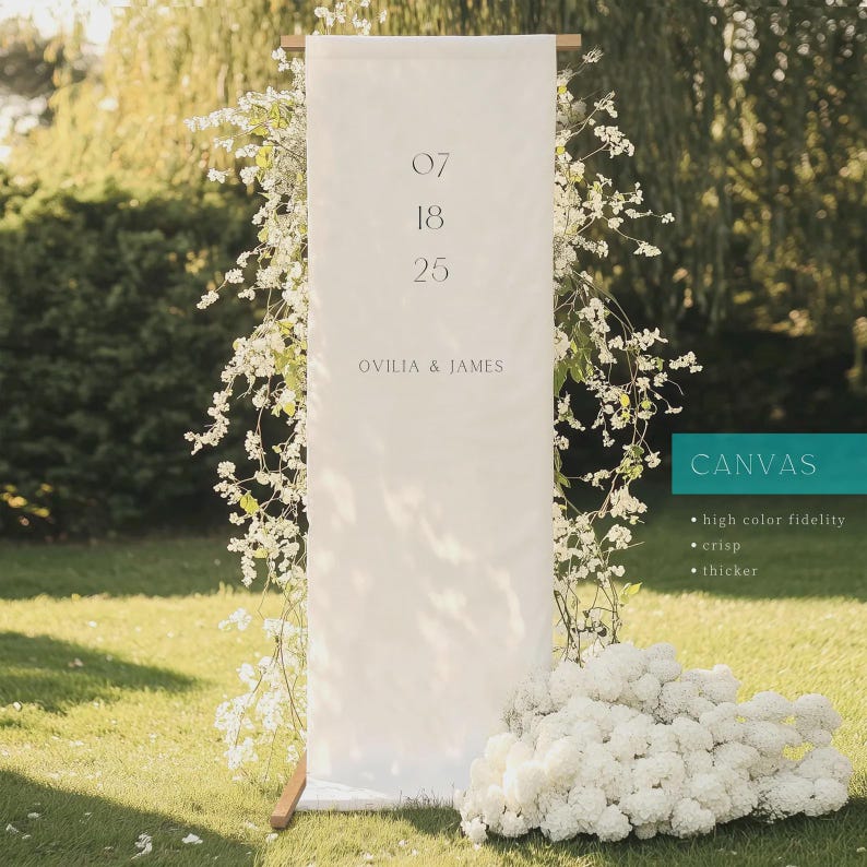 Puede incluir: Un estandarte rectangular alto de lona blanca suspendido en un marco de madera, con la fecha 07 18 25 y los nombres OVILIA & JAMES en texto gris oscuro. El estandarte est&aacute; adornado con arreglos florales blancos e incluye un cuadro de texto turquesa.