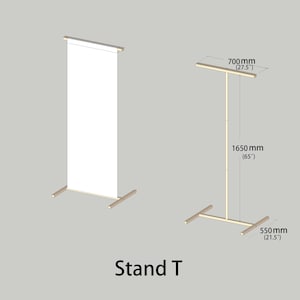 Puede incluir: Un soporte de exhibici&oacute;n de madera en forma de T etiquetado como Stand T. Una versi&oacute;n sostiene una pancarta vertical blanca. La estructura mide 700 mm de ancho, 1650 mm de alto y 550 mm de profundidad, con un poste vertical y una barra superior.
