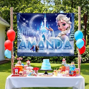 May include: A blue and white Frozen themed birthday banner with the text "Happy birthday Amanda" and an image of Elsa from the movie Frozen. The banner is hanging from a wooden pole and there is a table set up in front of it with a blue and white cake and other decorations.