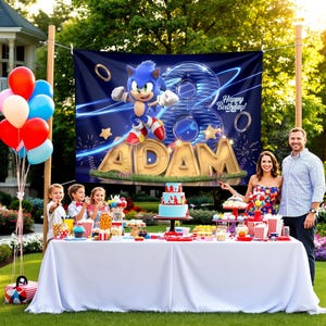 K&ouml;nnte beinhalten: Ein blaues und goldenes Geburtstagsbanner mit einer Comicfigur, Sonic the Hedgehog, und dem Namen "Adam" darauf. Das Banner h&auml;ngt an einem Pfosten vor einem Tisch mit einem Geburtstagskuchen und anderen Dekorationen.