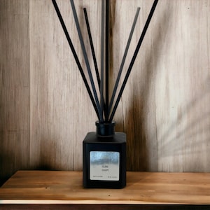 May include: Black diffuser bottle with black reeds and a silver label that reads "Island Escape".