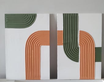 May include: Two abstract paintings with a white background and geometric shapes in shades of green and orange. The shapes are textured and appear to be made of paint.