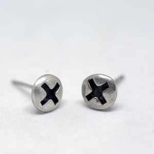 May include: A pair of silver stud earrings with a black cross design.