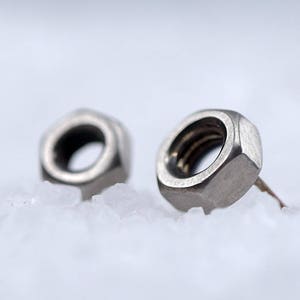 May include: A pair of silver metal earrings shaped like hexagonal nuts.