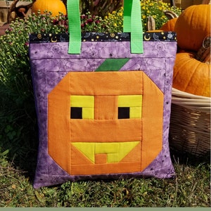 May include: A purple tote bag with a green handle and a patchwork pumpkin design. The pumpkin has a yellow smiling face with black eyes. The bag is labeled "Pumpkin Tote Bag" and "sew fun" with the website address "www.sewfun.com" and the number "#126".
