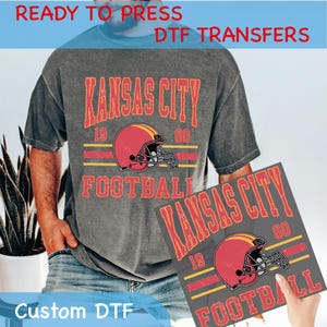 以下が含まれることがあります： カンザスシティチーフスのロゴをヴィンテージスタイルでデザインしたグレーのTシャツ。チーム名、19と60の数字、フットボールのヘルメットが描かれています。「Custom DTF」というテキストが画像の左下隅に表示されています。