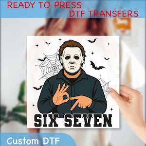 May include: A white square DTF transfer featuring a character in a mask, surrounded by bats and spiderwebs. The text "SIX SEVEN" is below the character. The words "READY TO PRESS DTF TRANSFERS" and "Custom DTF" are at the top and bottom.