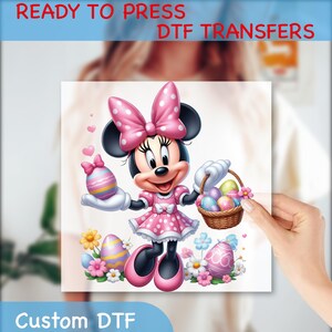 May include: A pink and white polka dot dress with a pink bow on top of Minnie Mouse's head. She is holding a basket of colorful Easter eggs and a single Easter egg in her other hand. The background is white with pink flowers.
