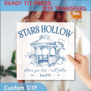 May include: A white DTF transfer featuring a blue gazebo design with the words "STARS HOLLOW" above it. Below the gazebo, the text reads "Where you lead, I will follow" and "Est.1779". The words "READY TO PRESS DTF TRANSFERS" and "Custom DTF" are also visible.