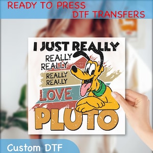 May include: A square DTF transfer featuring Pluto, the Disney cartoon dog, with the text "I JUST REALLY REALLY REALLY REALLY LOVE PLUTO." The design has a vintage, distressed look with a color palette of yellow, red, green, and brown. The words "READY TO PRESS DTF TRANSFERS" and "Custom DTF" are also visible.