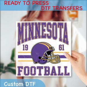 May include: A square DTF transfer featuring the word "MINNESOTA" in purple, with a purple and gold football helmet. The text "19 61 FOOTBALL" is also included. The words "READY TO PRESS DTF TRANSFERS" and "Custom DTF" are also present.