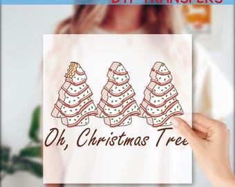 Pode incluir: Transferência DTF branca com três desenhos de árvores de Natal, detalhes em vermelho e verde, e o texto "Oh, Christmas Tree". A parte superior diz "Ready to Press DTF Transfers", e a inferior diz "Custom DTF".