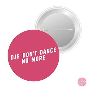 May include: A round, pink button with the text "DJs Don't Dance No More" in white, angled text. The button is shown next to a silver-colored pin back.
