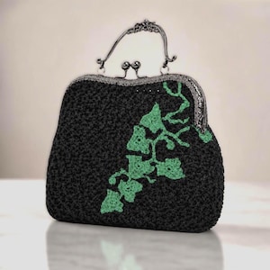 May include: A black crocheted handbag featuring a light green ivy leaf pattern on the front. The bag has a dark metallic frame with a decorative arched handle and a dual ball clasp closure mechanism at the top center of the frame.