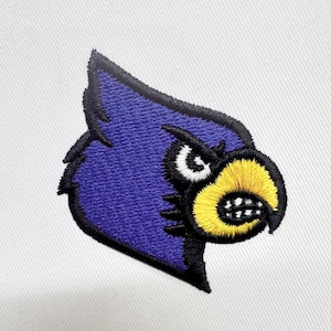 May include: Embroidered patch of a purple cardinal with a yellow beak and black eyes. The cardinal is looking to the right with an angry expression.