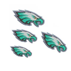 May include: Four embroidered eagle head patches in teal, silver, and gold, with grey outlines. The eagle's eye is yellow. The patches are different sizes and are set against a white background.