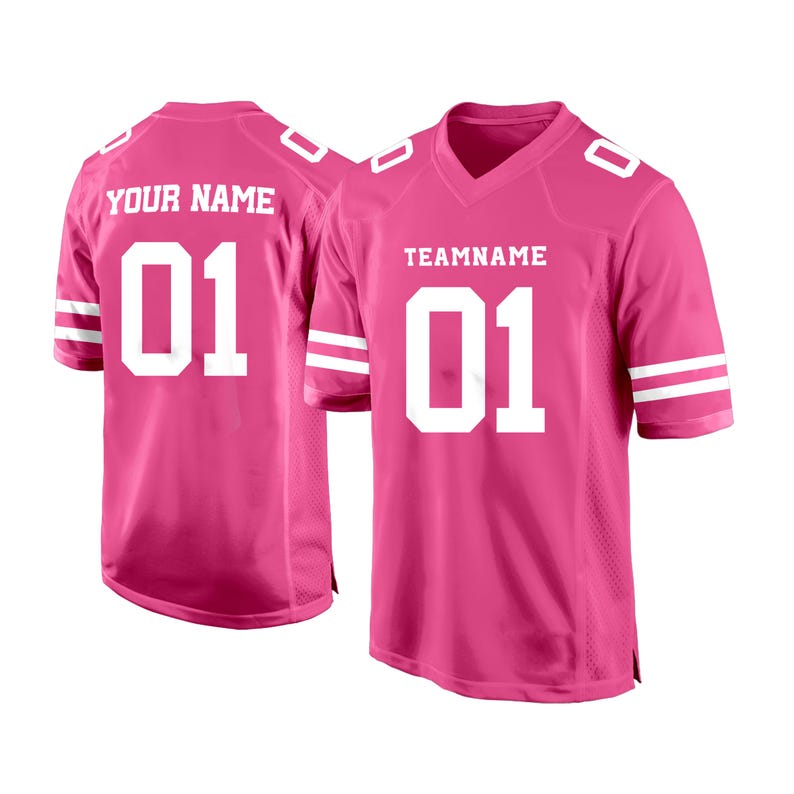 May include: Two pink football jerseys with white numbers and stripes. The jersey on the left says "YOUR NAME" and "01". The jersey on the right says "TEAMNAME" and "01".