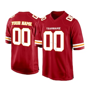 May include: Red football jersey with white and gold trim. The jersey has a white number "00" on the front and the text "TEAMNAME" above the number. The back of the jersey has a white number "00" and the text "YOUR NAME" above the number.