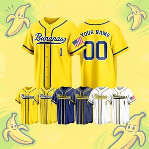 Puede incluir: Una colección de camisetas de béisbol en amarillo, azul marino y blanco. Las camisetas presentan la palabra "Bananas" en cursiva, junto con el número "1" o "00". Algunas camisetas tienen un parche de la bandera estadounidense. El fondo es amarillo con gráficos de plátanos.