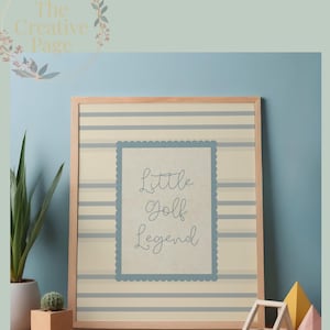Puede incluir: Una impresión artística enmarcada con un marco de madera clara. La impresión presenta un fondo a rayas con un borde festoneado azul alrededor del texto "Little Golf Legend". La parte superior del marco tiene el texto "High-Resolution, Digital Download Wall Art".