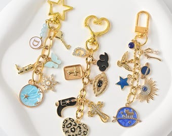 May include: Three gold-coloured keyrings with assorted charms. Charms include a star, heart, and a clasp. Each keyring has multiple charms, including a butterfly, a key, a cross, a star, and a heart with a leopard print.