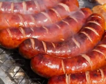 May include: Close-up of several grilled sausages on a metal rack. The sausages are brown and have grill marks. There is smoke coming from the sausages.