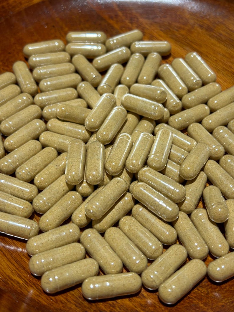 Peut inclure: Un bol rempli d'une grande quantit&eacute; de capsules brunes. Les capsules sont translucides et remplies d'une poudre brun clair.