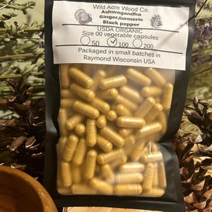 Peut inclure: Un sac refermable noir rempli de capsules jaunes. Le sac porte une &eacute;tiquette blanche sur laquelle est inscrit "Wild Acre Wood Co. Ashwagandha Gingembre, curcuma Poivre noir USDA ORGANIC Taille 00 capsules v&eacute;g&eacute;tales 50 100 200 Conditionn&eacute; en petits lots &agrave; Raymond Wisconsin USA".