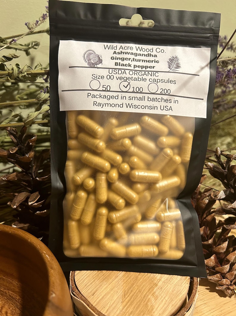 Peut inclure: Un sac refermable noir rempli de capsules jaunes. Le sac porte une &eacute;tiquette blanche sur laquelle est inscrit "Wild Acre Wood Co. Ashwagandha Gingembre, curcuma Poivre noir USDA ORGANIC Taille 00 capsules v&eacute;g&eacute;tales 50 100 200 Conditionn&eacute; en petits lots &agrave; Raymond Wisconsin USA".