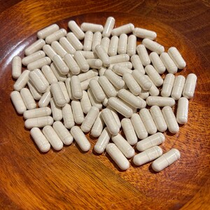 May include: A wooden bowl filled with a large quantity of white capsules.