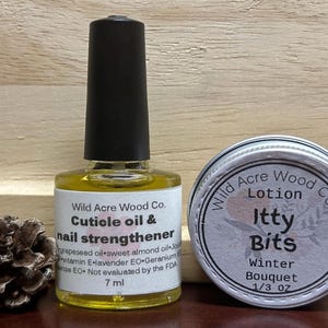 May include: Two small bottles of beauty products. A clear glass bottle with a black cap contains cuticle oil and nail strengthener. A silver tin contains a lotion called "Itty Bits Winter Bouquet".