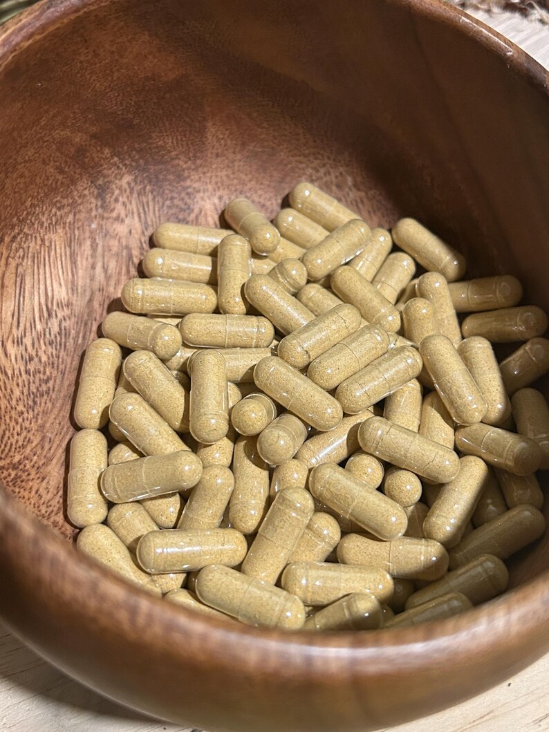 Peut inclure: Un bol en bois rempli d'une grande quantit&eacute; de capsules transparentes contenant une poudre brun clair.