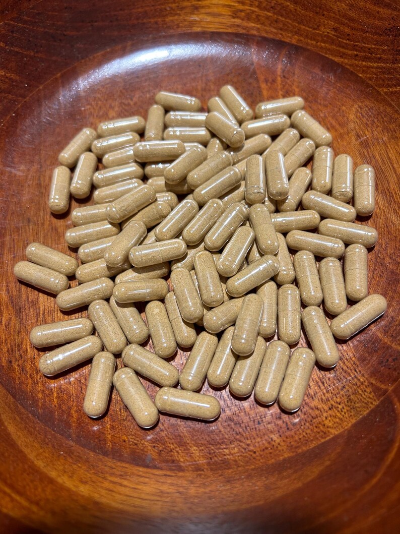 Peut inclure: Un bol en bois rempli d'une grande quantit&eacute; de capsules brunes. Les capsules sont translucides et semblent &ecirc;tre remplies d'une poudre brune.