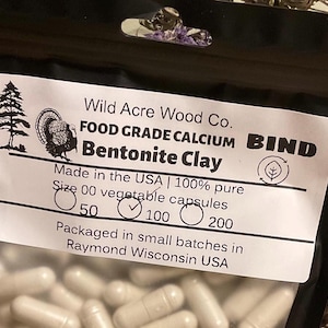 May include: A black bag of Bentonite Clay capsules from Wild Acre Wood Co. The label includes text, a turkey illustration, and the text "Made in the USA". The capsules are size 00 and come in 50, 100, or 200 count packages.