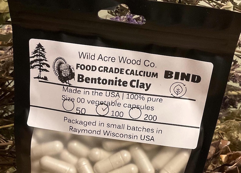 May include: A black bag of Bentonite Clay capsules from Wild Acre Wood Co. The label includes text, a turkey illustration, and the text "Made in the USA". The capsules are size 00 and come in 50, 100, or 200 count packages.
