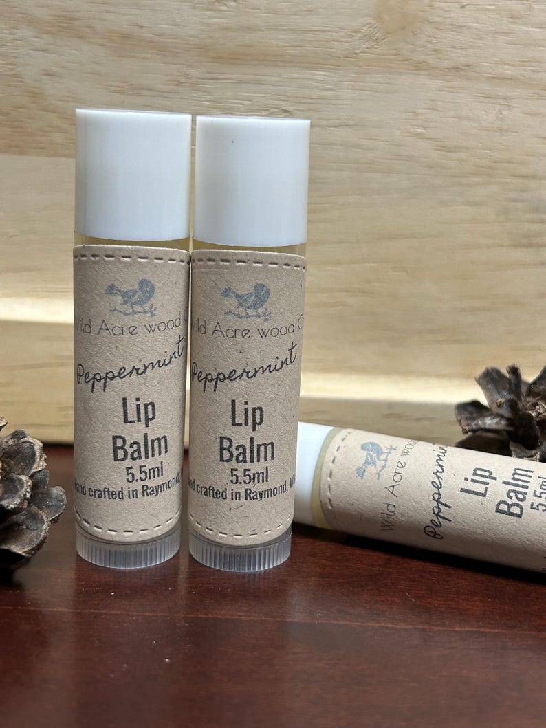 Absolutely perfect 100% natural organic lip balms perfect for the time of year ahead of us!  WINTER! To lip balms stand upright, one is lying down with two scotch pine cones in the background.quench your thirsty lips with this moisturizing lip balm.