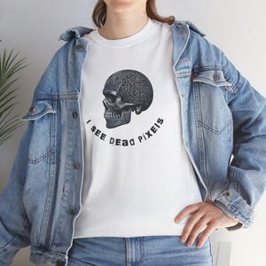 May include: White t-shirt with a black and white skull graphic. The skull has a circuit board design inside. The text "I see dead pixels" is printed below the skull.